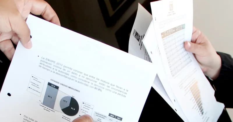 Two people holding printed reports with charts