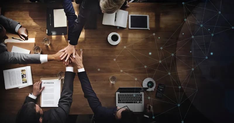 Colleagues stacking their hands over a meeting table