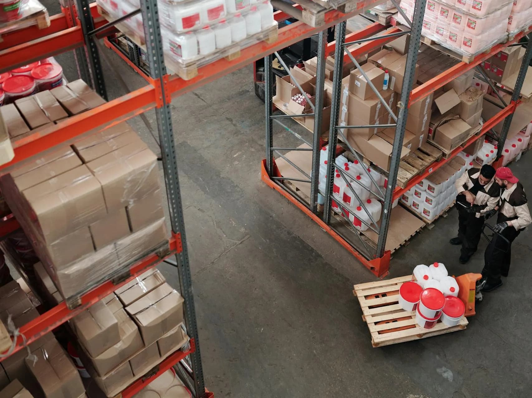 Depoda yüksek raflar arasında çalışanlar