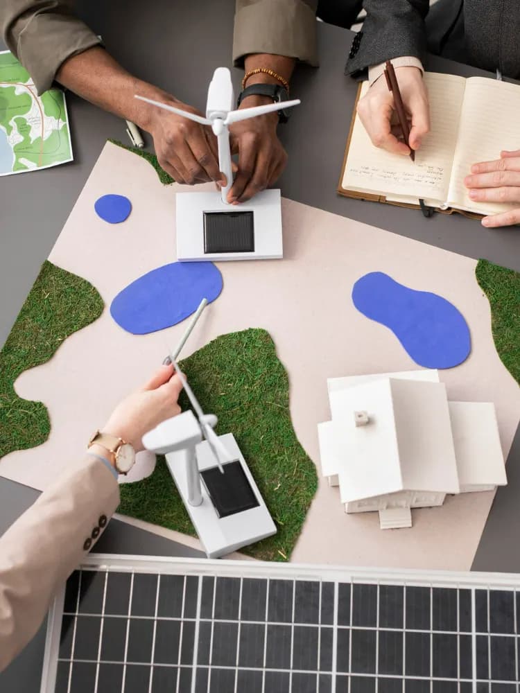 People planning with wind turbine and solar panel models on a table